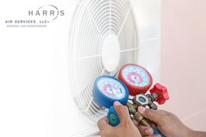 Hands on an HVAC gauge, testing a heat pump. Harris Air logo in top left corner.