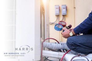 Harris Air Services technician inspecting an HVAC unit. Harris Air logo in bottom left corner.