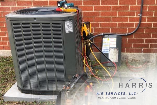 AC unit on the outside of a brick home, with the Harris Air Services logo in the bottom right corner. 
