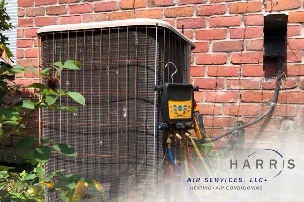 Outdoor AC unit beside a brick home. Harris Air logo in bottom right corner.